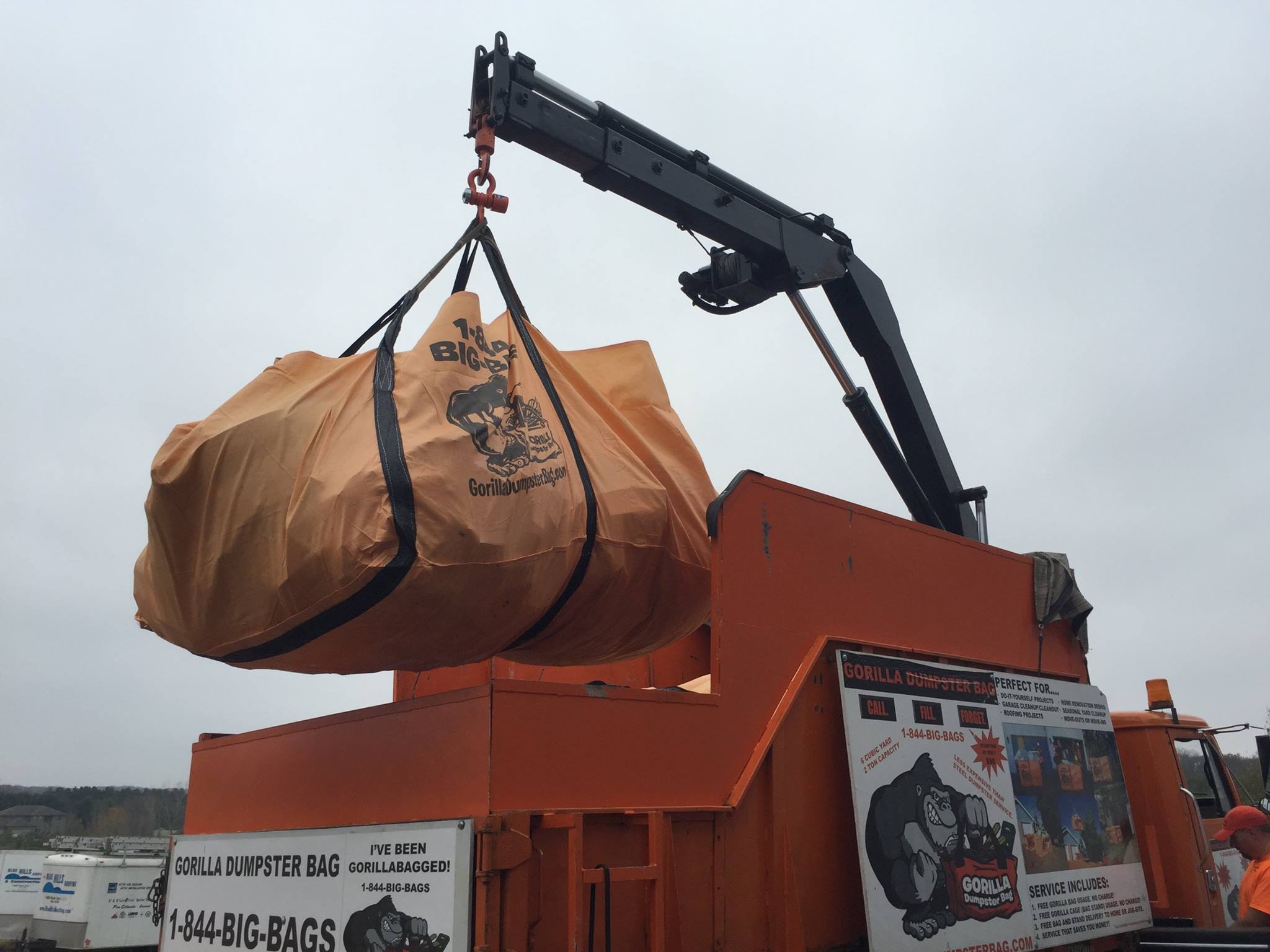 Homeowner loading debris into a cheap dumpster bag frame.